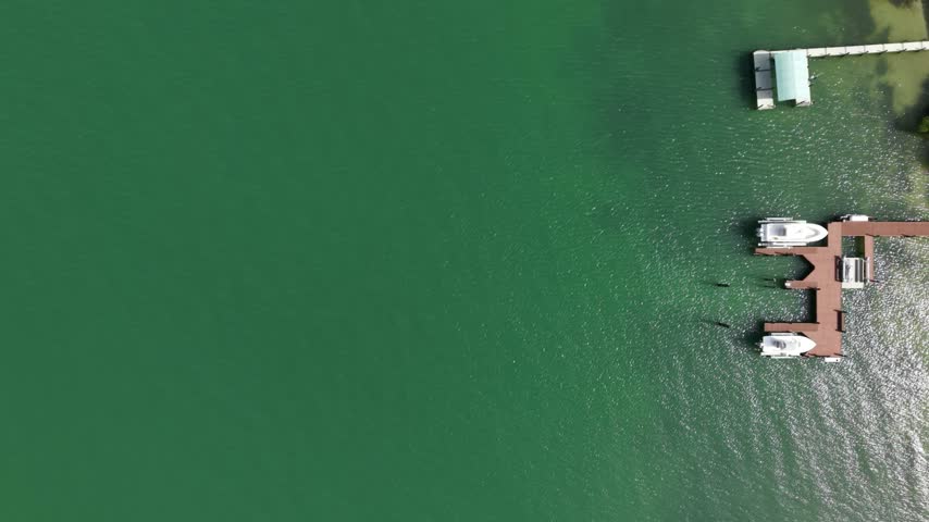 Aerial view of a waterfront dock with boats on green water