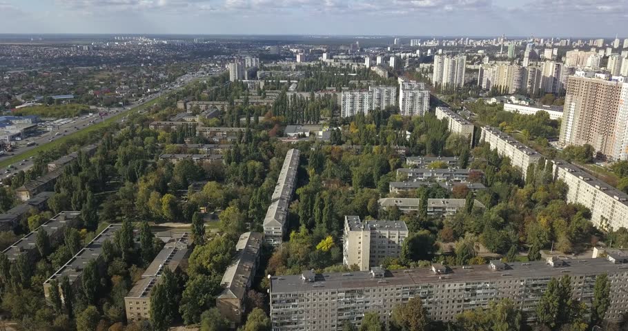 Aerial panorama of Kyiv, Ukraine, featuring residential districts, apartment buildings, private homes, extensive green areas and urban roads. Wide drone view of the metropolitan landscape