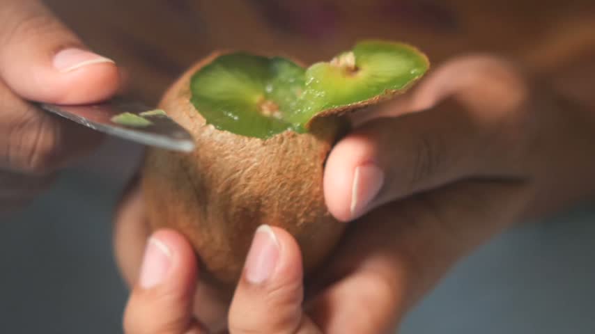 closeup of cutting kiwi fruit with a knife 