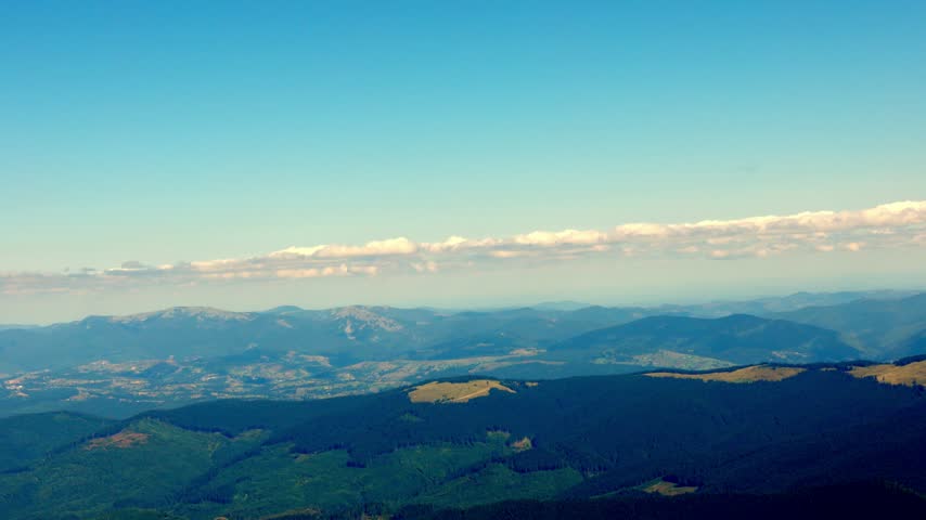 Aerial view of majestic mountain peaks covered with snow under a dramatic cloudy sky.