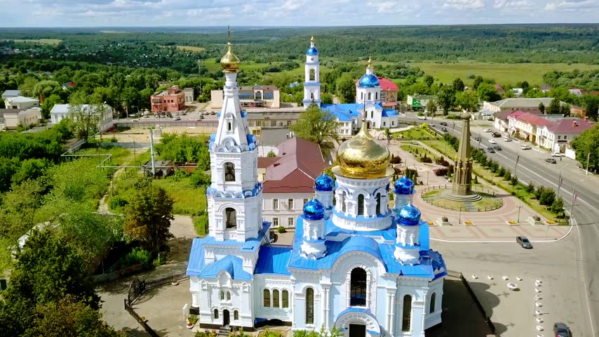 Aerial view of a traditional Russian Orthodox Church with blue domes and a bell tower in a provincial town.