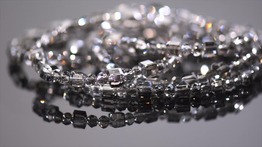 Crystals bracelet or necklace, gems, diamonds over black background, beautiful gems, rhinestones, brilliants sparkling with colorful caustics, rainbow lights. Moissanite. Zirconia rotating