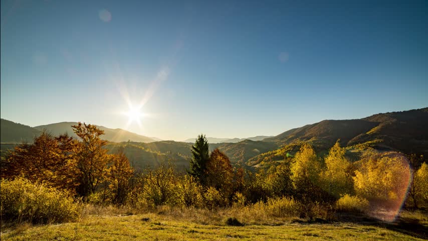 Bright sunset behind mountains in highland at autumn dusk