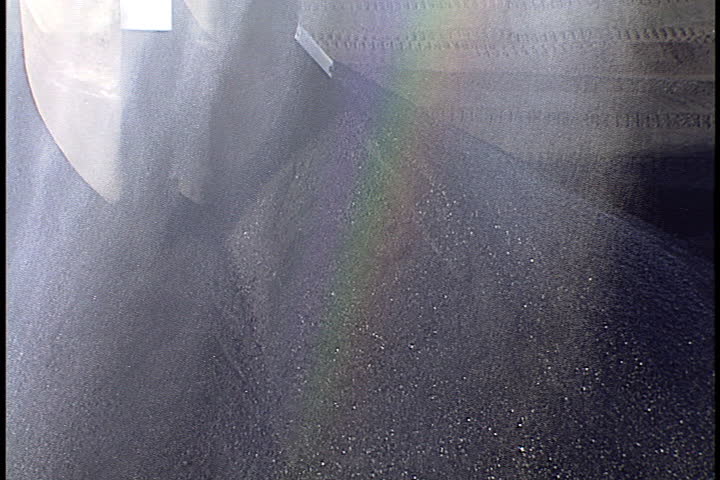 Water pours down from silo as bulldozers push coal on enormous coal pile in Metropolis, Illinois.