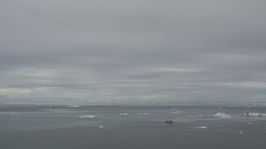 Red Boat Crossing Ilulissat Icefjord Among Icebergs in Greenland