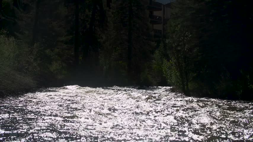 Silhouette of kayaker racing fast down a rushing river