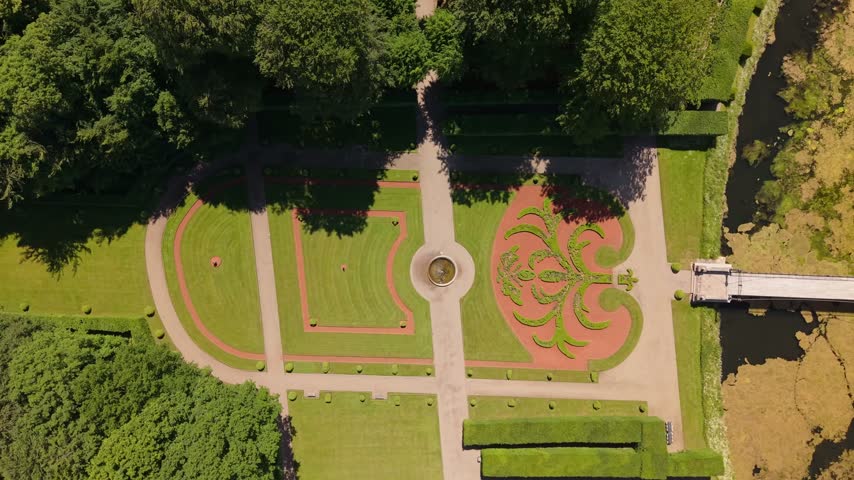 Bird’s-eye drone footage of Egeskov Castle surrounded by beautifully designed gardens, ornamental lakes, winding paths, and lush Danish countryside.