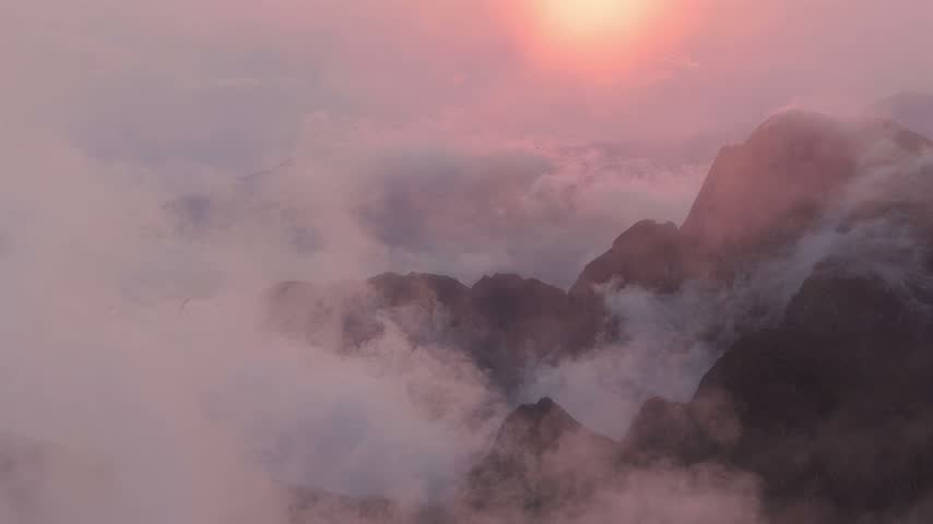 Majestic mountain range shrouded in ethereal mist during a vibrant sunrise, creating a sense of awe and natural beauty