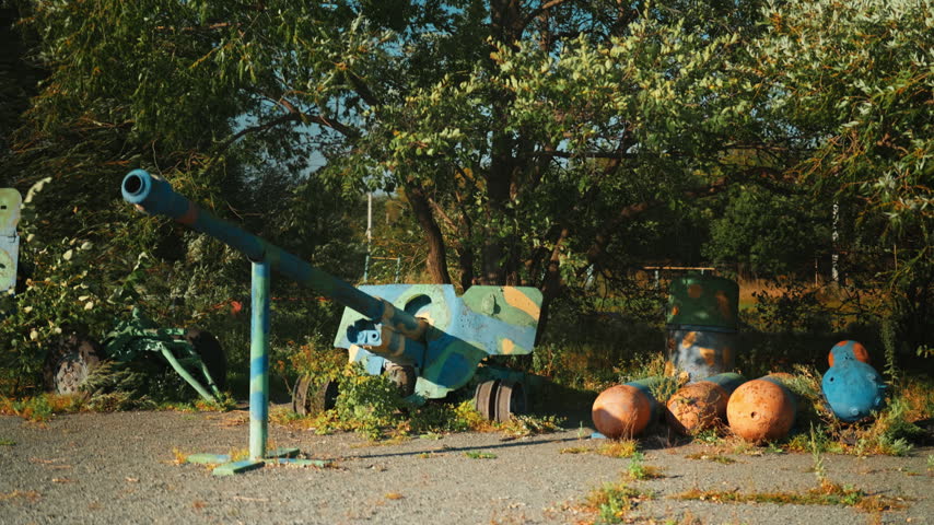 Obsolete, abandoned, and rusty combat guns stand amidst the natural landscape. A graveyard of weaponry. An echo of war. The aftermath of war.