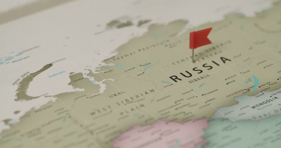 Close-up view of a red pin with a flag marking the country of Russia on a vintage-style world map, indicating a destination for travel, politics, or strategic planning