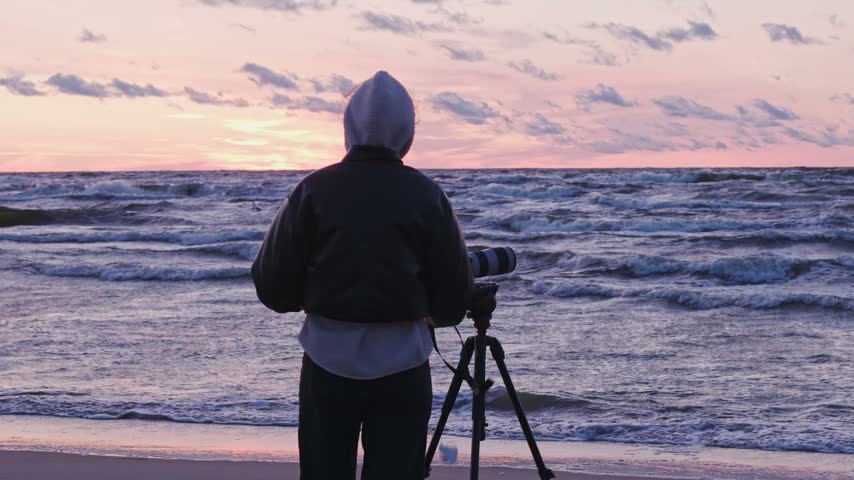 Photographer watches kitesurfer leap through pink Baltic Sea sunset waves