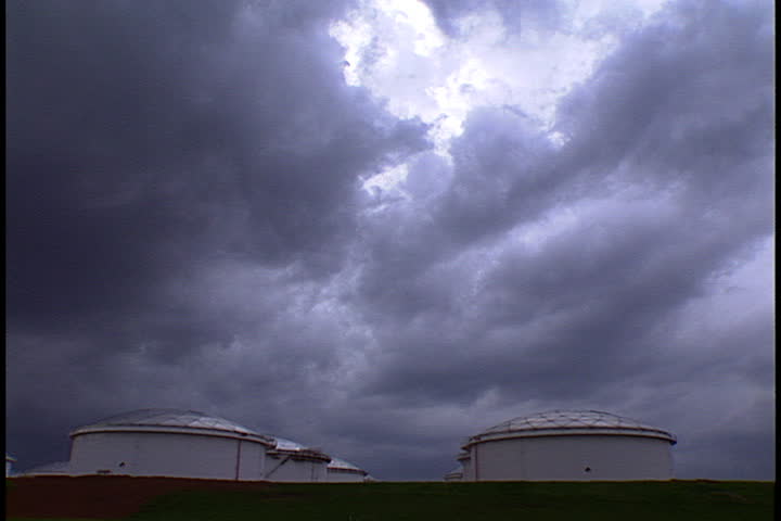 Pan across field of oil storage tanks under storm clouds in Atlanta, Georgia.
