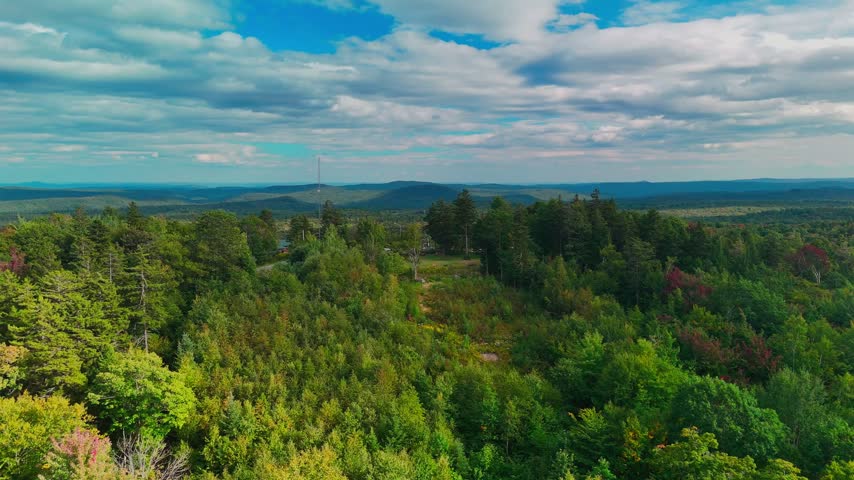 Aerial view of Hogback Mountain Conservation Area, Marlboro, Vermont with rolling forested hills, distant mountains, and dramatic cloudy sky, representing wilderness and environmental preservation.