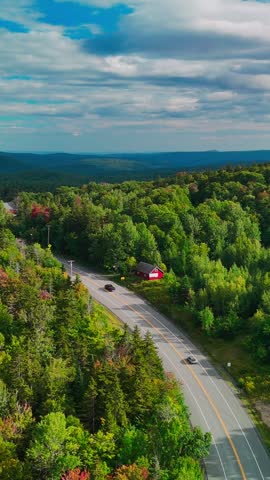 Aerial view of a winding road through Hogback Mountain forest, Marlboro, Vermont with rolling hills and distant mountains, representing wilderness, travel, and conservation. 4K. Vertical.