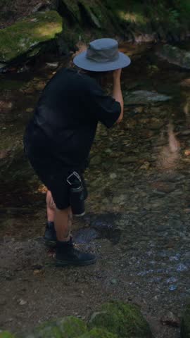 Hiker washing his face in a rocky stream at Tannery Falls, Savoy Mountain State Forest, Massachusetts. Hiking and nature travel. 4K. Vertical.