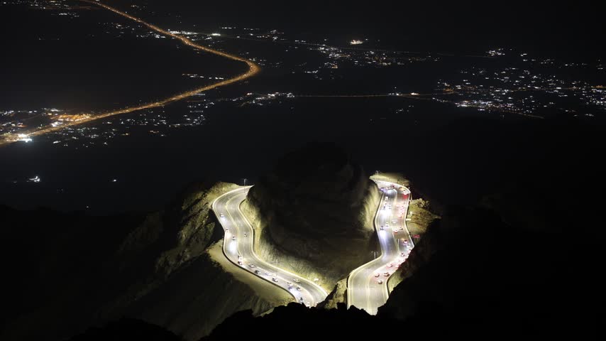 Taif,  Saudi Arabia_ Night time-lapse of illuminated winding mountain road in Al Hada, Taif with city lights and traffic, 4K footage video