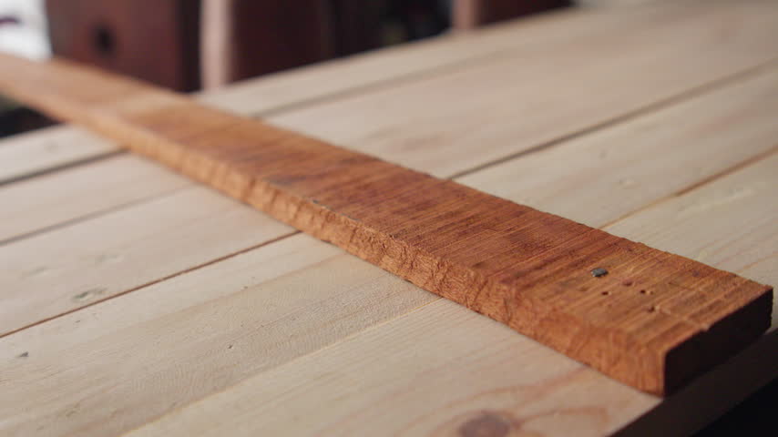Carpenter driving a nail into a wooden plank with a hammer, capturing woodworking, carpentry, construction, and skilled craftsmanship.
