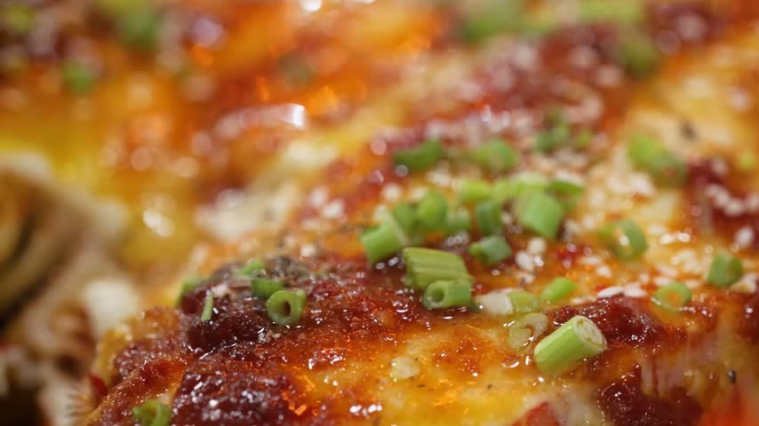 A macro, shallow depth-of-field shot of a freshly prepared Asian-style lobster covered in a rich, glossy red chili glaze.