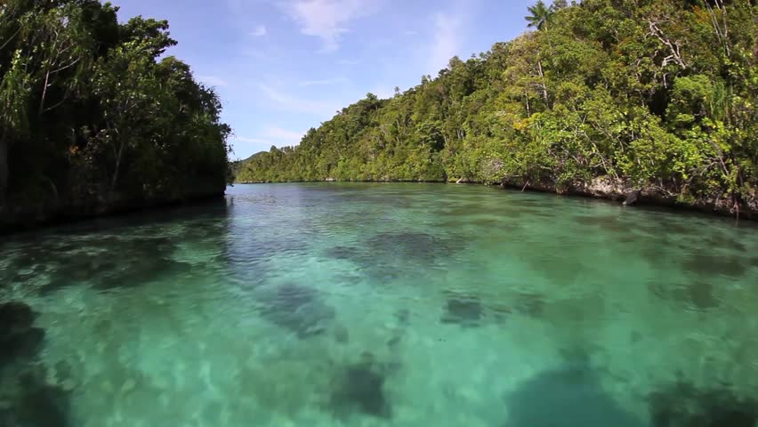 Rugged limestone islands, covered by tropical vegetation, rise amid a calm