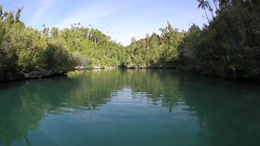 Rugged limestone islands, covered by tropical vegetation, rise amid a calm