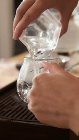 Ceramic tea set on a wooden tray with a glass pitcher and chopsticks, close up scene of tea service in a cozy home dining space, traditional tableware arranged neatly.
