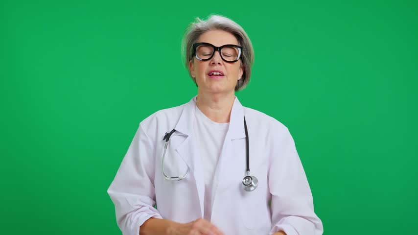 Senior professional physician with arms crossed posing in a studio with a green screen background