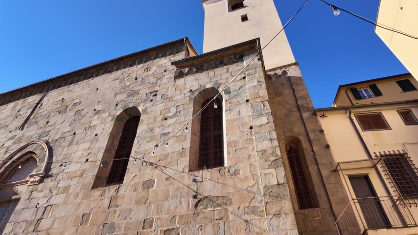 Stone church facade with tower and leafy tree. Cinque Terre, Italy.