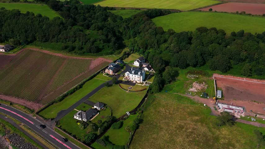 Drone view, large country residence set among farmland between Ardrossan and West Kilbride on the A78 in North Ayrshire, Scotland, with landscaped grounds, driveway and surrounding fields