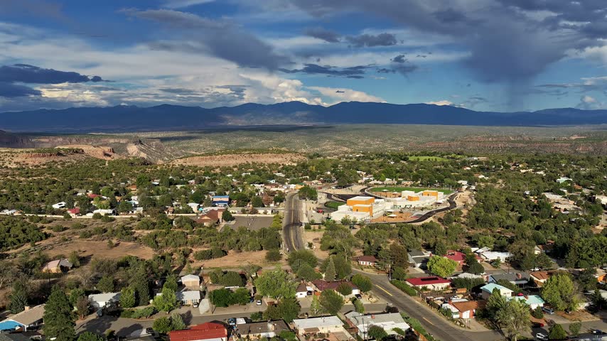 4K drone weather time lapse rising over the town of White Rock, New Mexico. Dramatic clouds sweep across the sky above the vast desert valley, looking out toward the distant Mt Baldy.