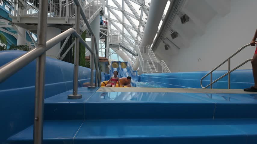 Dad and daughter at a water park after riding a slide. Father and child with an inflatable ring in a pool. Family fun and vacation concept.