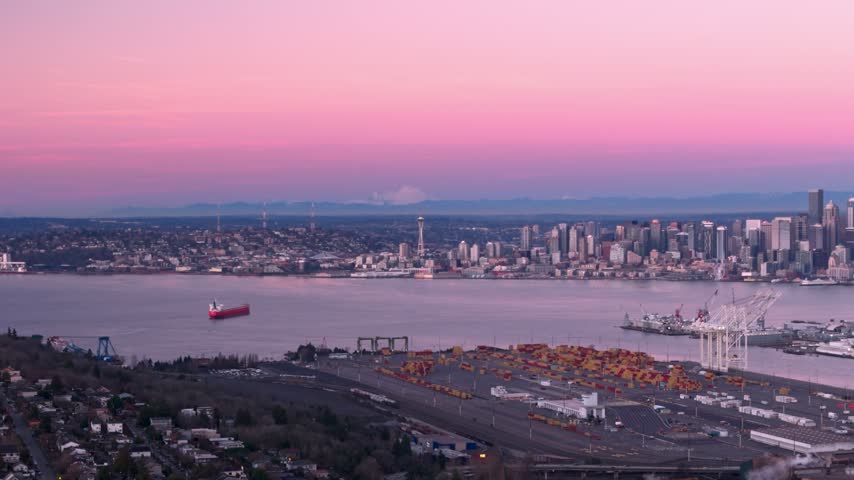 Wide establishing shot of the Seattle Space Needle and Port of Seattle during a pink sunrise.