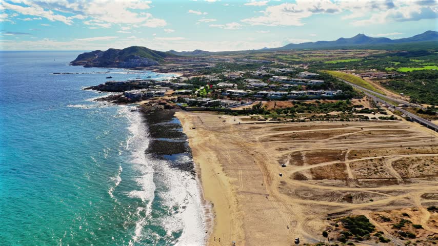 Aerial orbit around El Tule Beach overlooking Federal Highway 1, Pacific Ocean and luxury resorts along the Los Cabos coastline, Baja California Sur
