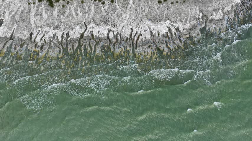 An aerial view of the white, salty soil exposed as the water level in Lake Burdur receded due to drought, and the waves crashing against the shore.	

