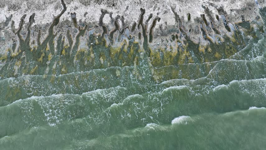 An aerial view of the white, salty soil exposed as the water level in Lake Burdur receded due to drought, and the waves crashing against the shore.