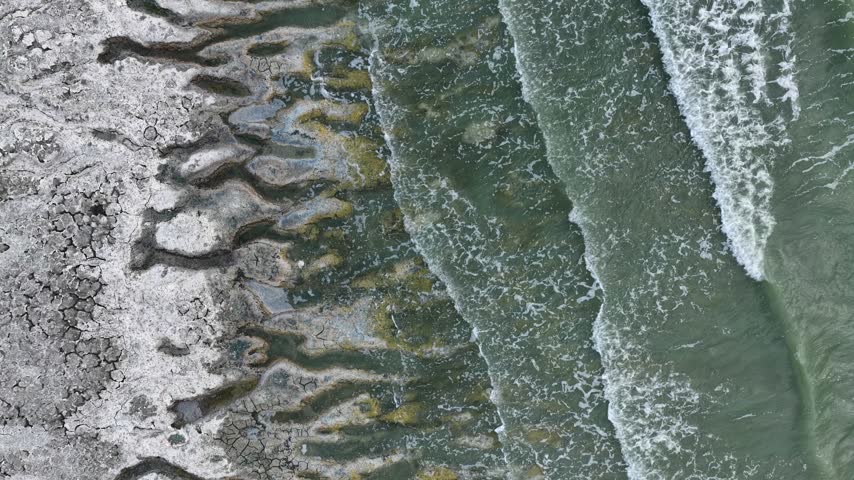 An aerial view of the white, salty soil exposed as the water level in Lake Burdur receded due to drought, and the waves crashing against the shore.	
