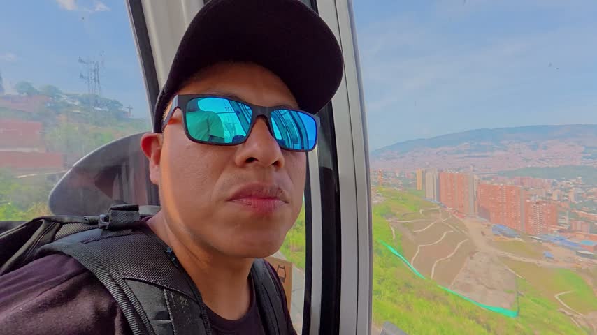 Young man smiling and looking at the camera while riding the medellin metrocable