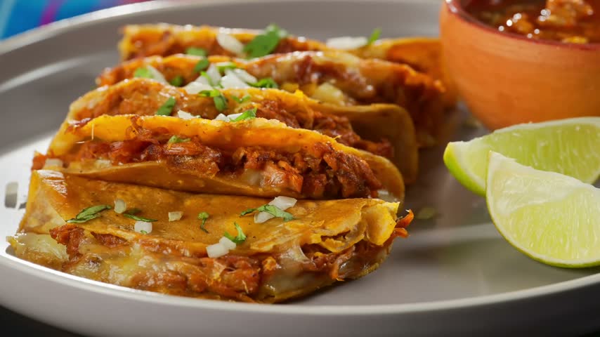 Appetizing plate of fried shredded pork tacos with chopped onions and fresh herbs, ready to serve
