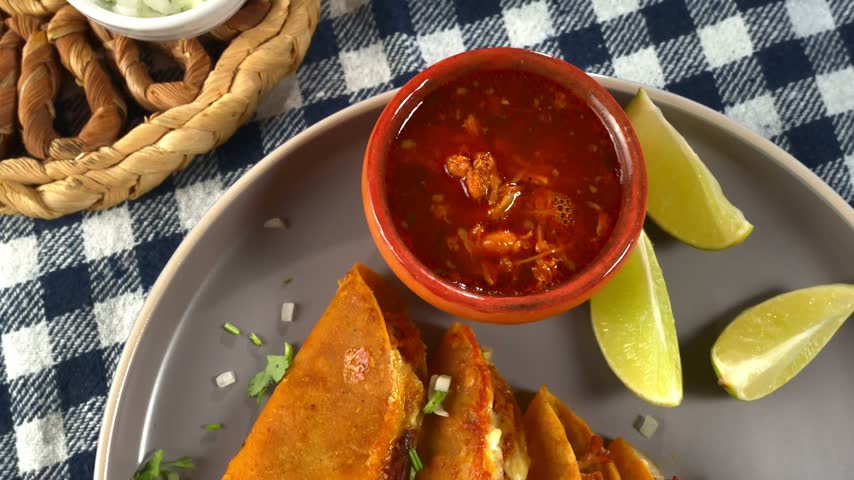 Mexican Cuisine. Plate of Quesabirria tacos with consommé, lime and onions.
