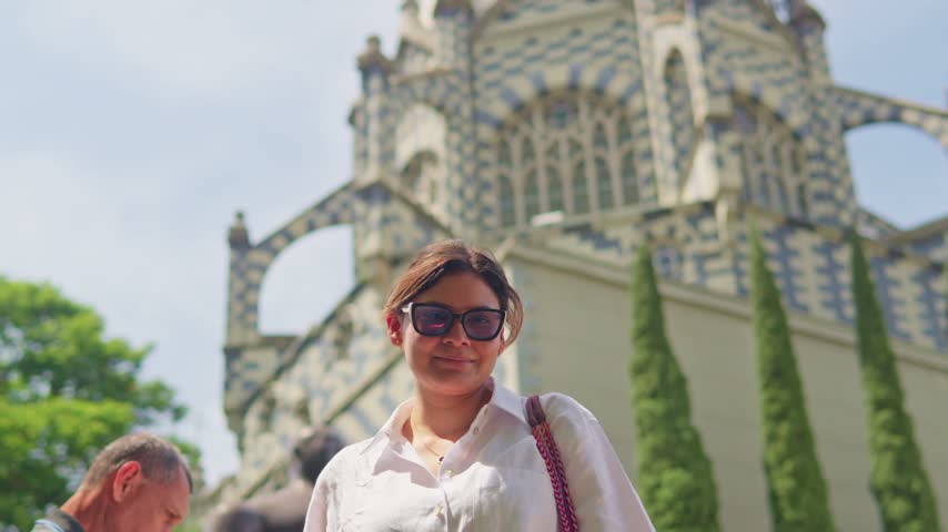 Latina tourist smiling and walking in front of the palace of culture in medellin, colombia
