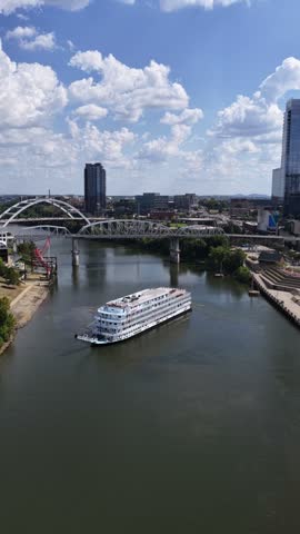 Paddlewheel boat turning on the Cumberland River in Nashville, Tennessee, with a sightseeing river cruise. Captured with a slow drone aerial orbit of the boat