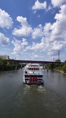 Aerial drone video captured in vertical orientation of a paddle wheel boat river cruise paddling down the Cumberland River in Nashville, Tennessee