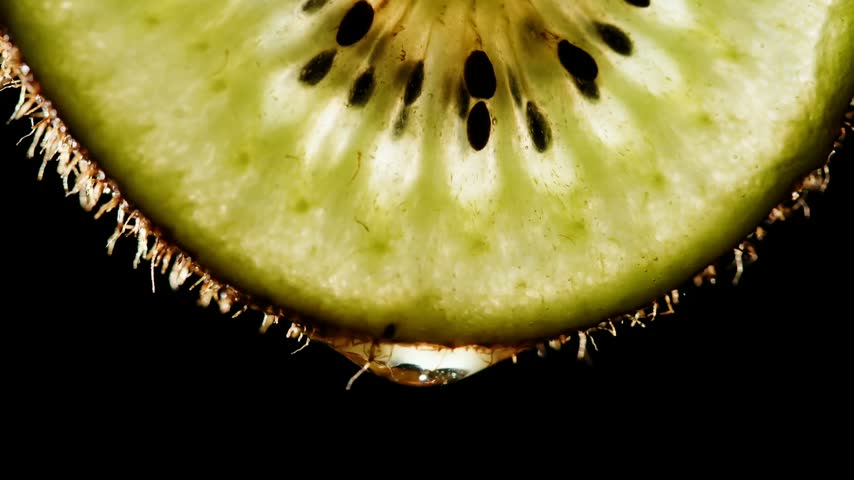 Macro close up fresh green kiwi fruit slice dripping juice water drop on black background juicy healthy organic food 4K