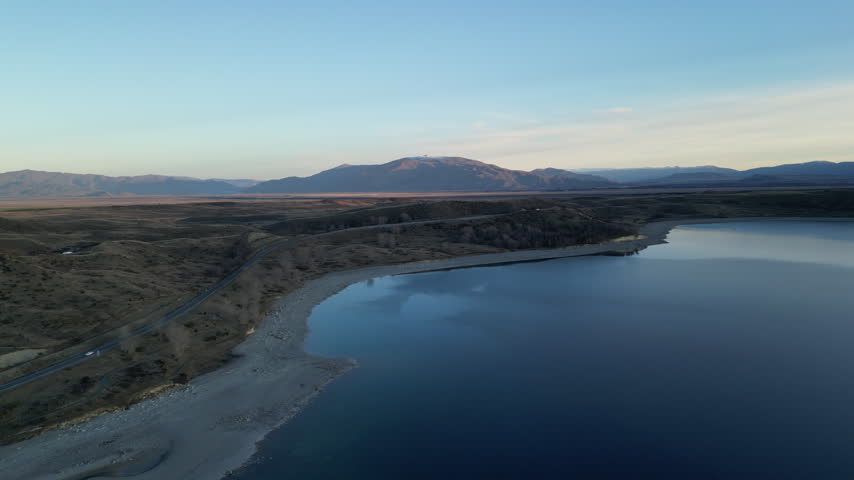 Beautiful aerial sunset view of Lake Pukaki New Zealand displays snow covered Southern Alps and dramatic mountain ranges across a peaceful natural Pacific landscape