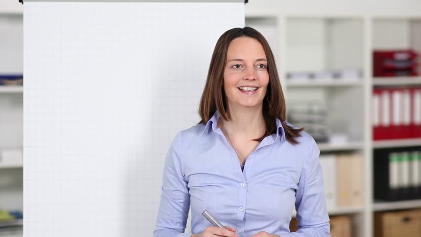 Businesswoman giving a presentation in a meeting standing in front of a blank white paper flipchart | Shutterstock HD Video #4184210