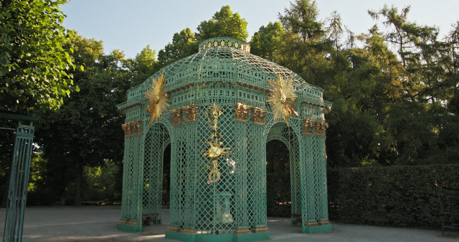 Gitterpavillon at Sanssouci Palace in Potsdam, Germany, with green latticework and gilded ornaments in a wooded garden.