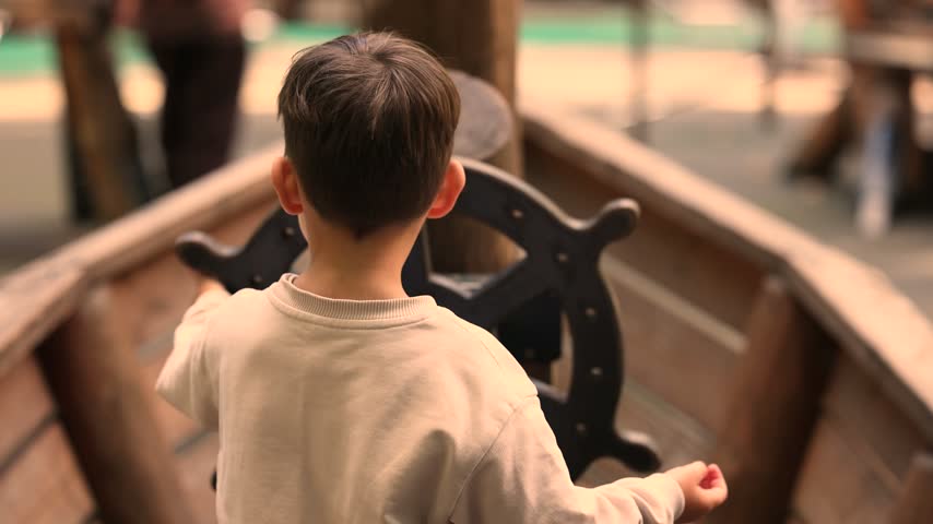 Danish adventure playground features boy steering pirate ship wheel