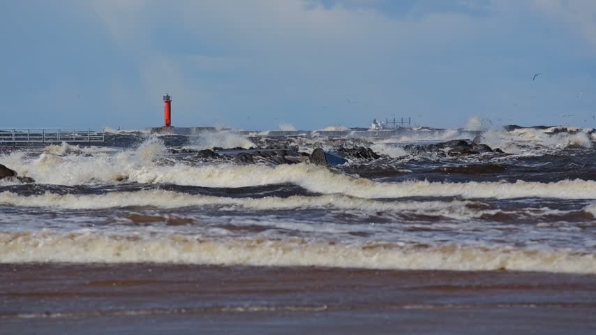 Powerful Baltic waves splash by Mangalsala breakwater as seagulls cross the sky