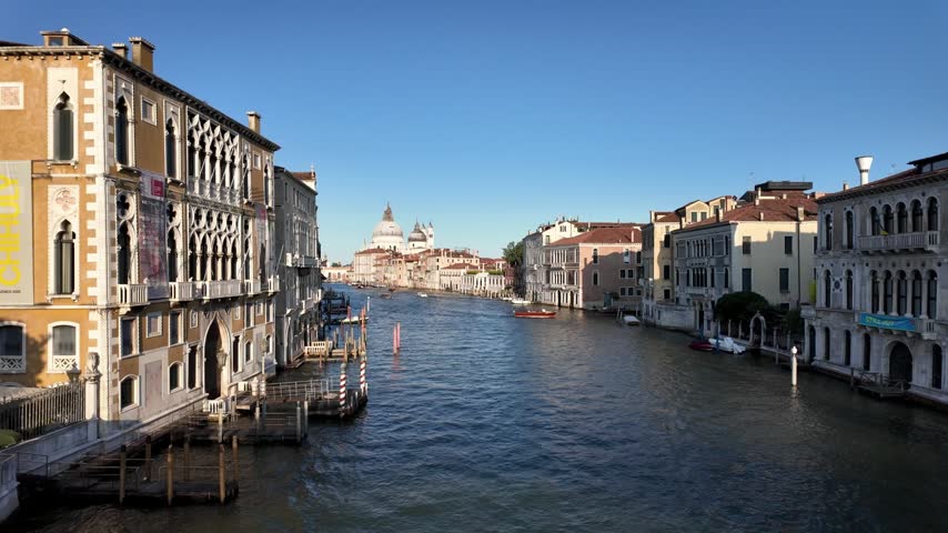 Busy Venetian waterfront near the entrance to Venice, with tourists, gondolas and boats surrounded by historic buildings along the Grand Canal
