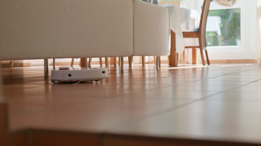 Robot vacuum cleaning a home vacuums and mops the brown tile floor low angle