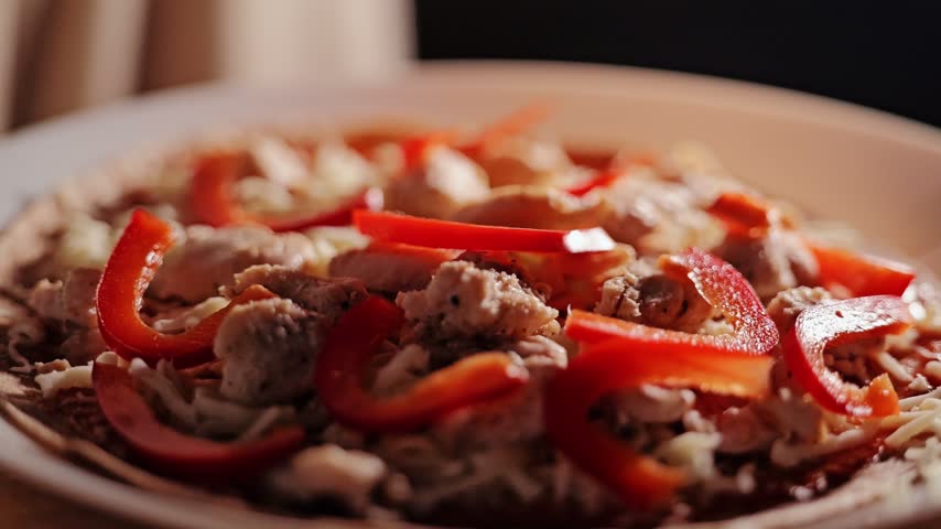 Homemade tortilla pizza gets its final onion topping before baking in the oven